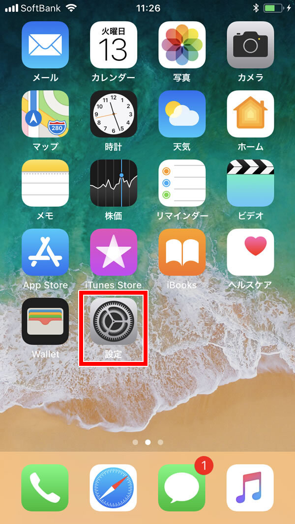 説明図：iPhoneホーム画面上の設定アプリのアイコンを示す画面。