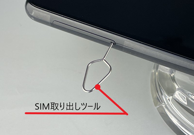 説明図：SIM取り出しツールを差し込んでいる図